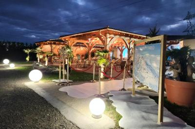 Espace intérieur en bois avec canapés, fauteuils, guirlande lumineuse et stand décoratif éclairé.