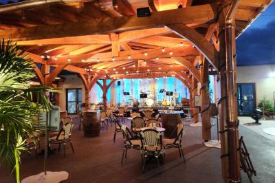 Espace intérieur en bois avec canapés, fauteuils, guirlande lumineuse et stand décoratif éclairé.