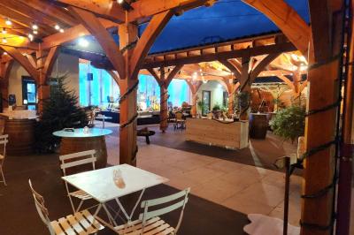 Espace intérieur en bois avec canapés, fauteuils, guirlande lumineuse et stand décoratif éclairé.