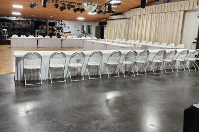 Espace intérieur en bois avec canapés, fauteuils, guirlande lumineuse et stand décoratif éclairé.