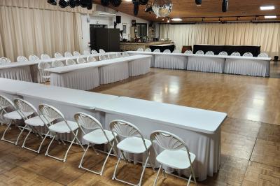 Espace intérieur en bois avec canapés, fauteuils, guirlande lumineuse et stand décoratif éclairé.