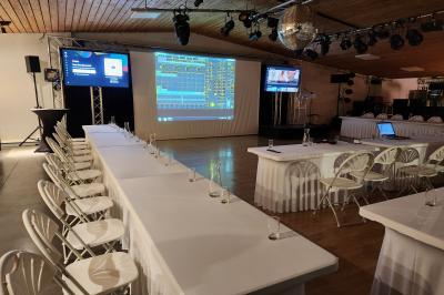 Espace intérieur en bois avec canapés, fauteuils, guirlande lumineuse et stand décoratif éclairé.