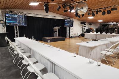 Espace intérieur en bois avec canapés, fauteuils, guirlande lumineuse et stand décoratif éclairé.