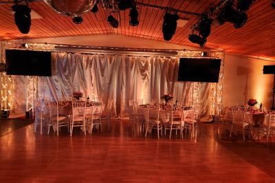 Espace intérieur en bois avec canapés, fauteuils, guirlande lumineuse et stand décoratif éclairé.