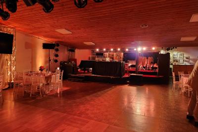 Espace intérieur en bois avec canapés, fauteuils, guirlande lumineuse et stand décoratif éclairé.