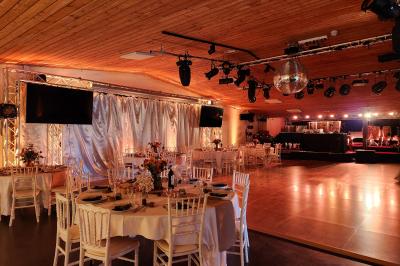 Espace intérieur en bois avec canapés, fauteuils, guirlande lumineuse et stand décoratif éclairé.