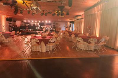 Espace intérieur en bois avec canapés, fauteuils, guirlande lumineuse et stand décoratif éclairé.