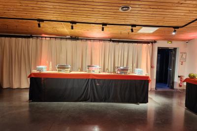 Espace intérieur en bois avec canapés, fauteuils, guirlande lumineuse et stand décoratif éclairé.