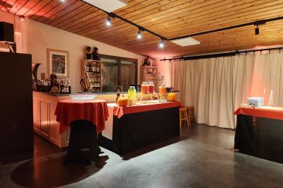 Espace intérieur en bois avec canapés, fauteuils, guirlande lumineuse et stand décoratif éclairé.