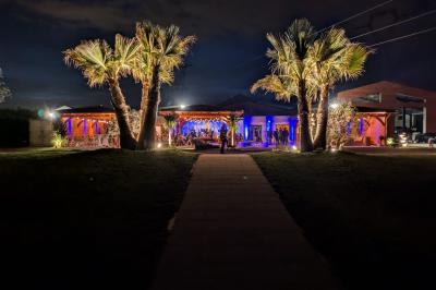 Espace intérieur en bois avec canapés, fauteuils, guirlande lumineuse et stand décoratif éclairé.
