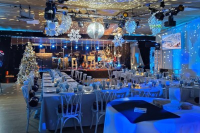 Un groupe de musiciens et chanteurs joue sur une scène éclairée dans une salle avec un public assis.