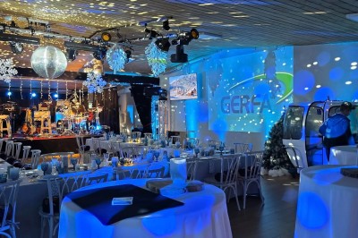 Un groupe de musiciens et chanteurs joue sur une scène éclairée dans une salle avec un public assis.