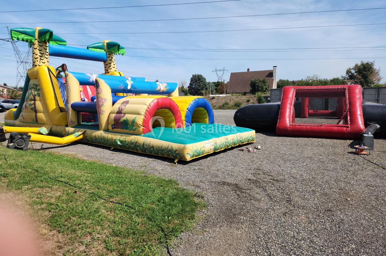 Structures gonflables colorées installées sur un terrain extérieur, comprenant un toboggan et une aire de jeu.