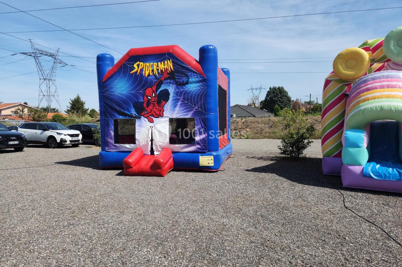 Structure gonflable sur le thème de Spider-Man installée en extérieur, à côté d'une autre structure colorée.