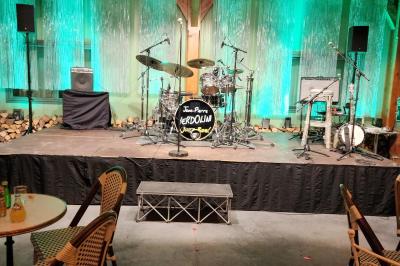 Un groupe de musiciens et chanteurs joue sur une scène éclairée dans une salle avec un public assis.