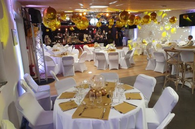 Un groupe de musiciens et chanteurs joue sur une scène éclairée dans une salle avec un public assis.