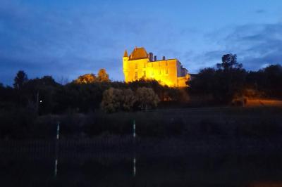 Château illuminé au sommet d'une colline, reflété dans l'eau calme au crépuscule.