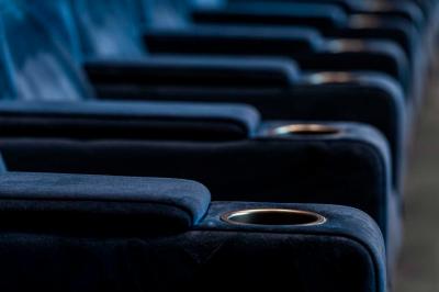 Façade d'un cinéma moderne avec terrasse extérieure équipée de tables hautes et tabourets.