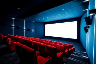 Façade d'un cinéma moderne avec terrasse extérieure équipée de tables hautes et tabourets.