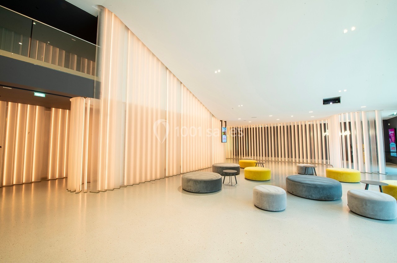 Espace intérieur moderne avec murs lumineux, sièges ronds colorés et sol clair.