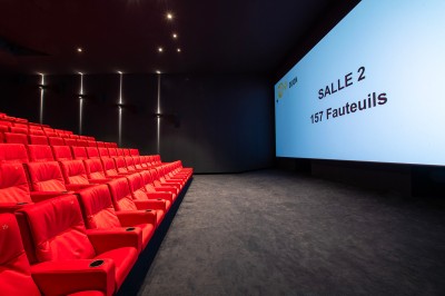 Salle de cinéma moderne avec écran large, sièges rouges et éclairage tamisé, affichant ’Pathé Dijon, Salle 9, 85 fauteuils’.