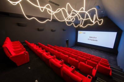 Salle de cinéma moderne avec écran large, sièges rouges et éclairage tamisé, affichant ’Pathé Dijon, Salle 9, 85 fauteuils’.