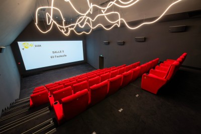 Salle de cinéma moderne avec écran large, sièges rouges et éclairage tamisé, affichant ’Pathé Dijon, Salle 9, 85 fauteuils’.