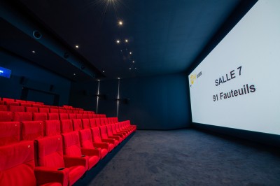 Salle de cinéma moderne avec écran large, sièges rouges et éclairage tamisé, affichant ’Pathé Dijon, Salle 9, 85 fauteuils’.