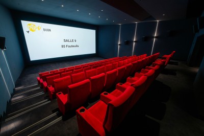 Salle de cinéma moderne avec écran large, sièges rouges et éclairage tamisé, affichant ’Pathé Dijon, Salle 9, 85 fauteuils’.