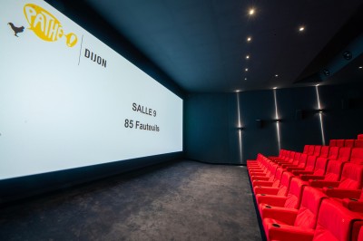 Salle de cinéma moderne avec écran large, sièges rouges et éclairage tamisé, affichant ’Pathé Dijon, Salle 9, 85 fauteuils’.