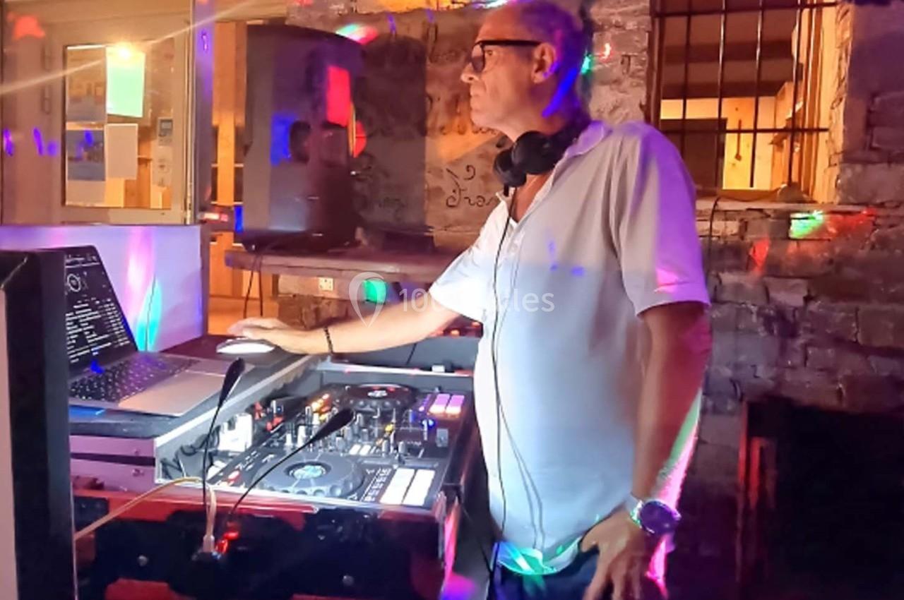 Un DJ mixe de la musique sur une console dans un espace éclairé par des lumières colorées.