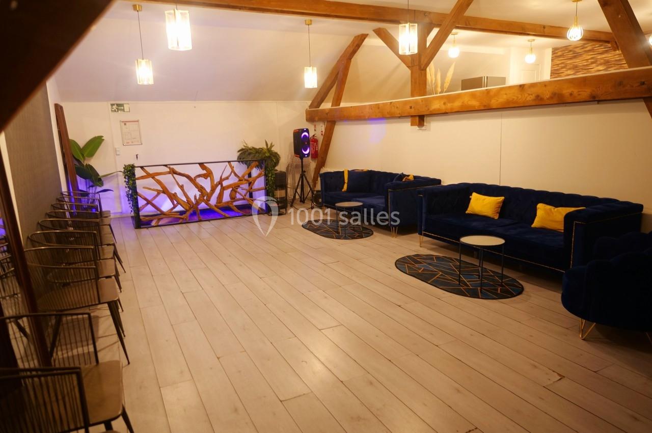 Salle lumineuse avec parquet clair, canapés bleus, coussins jaunes, tables basses et décoration en bois.