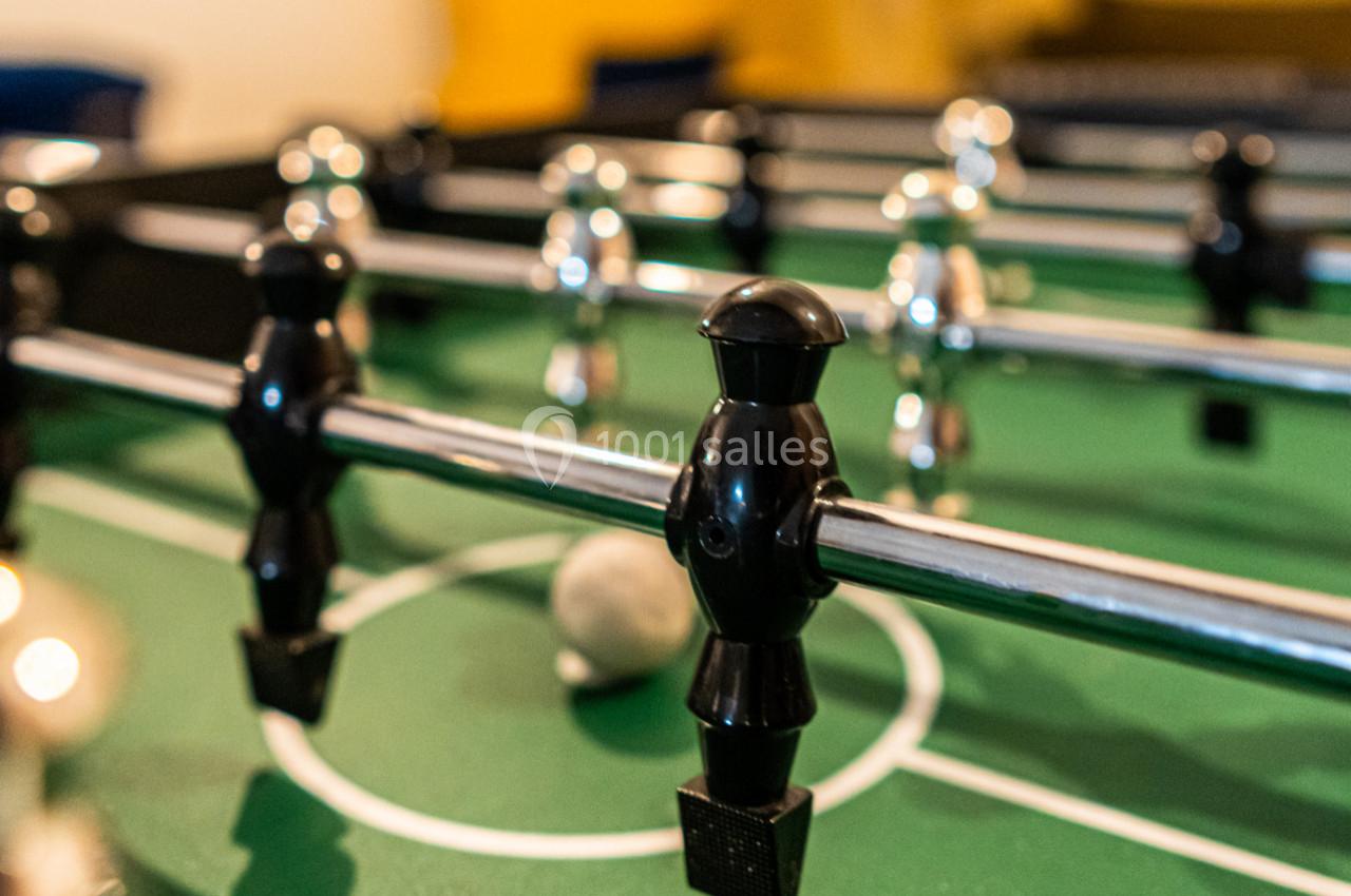 Joueurs de baby-foot noirs et argentés fixés sur des barres métalliques au-dessus d'un terrain vert.