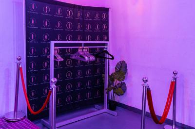 Miniature VESTIAIRE Studio éclairé en violet avec un canapé, une table basse et des coussins au sol, logo Netflix projeté sur le mur.