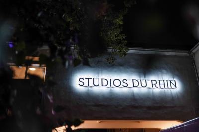 Un DJ mixe sur une scène éclairée par des lumières colorées, face à une foule dansante dans une salle sombre.