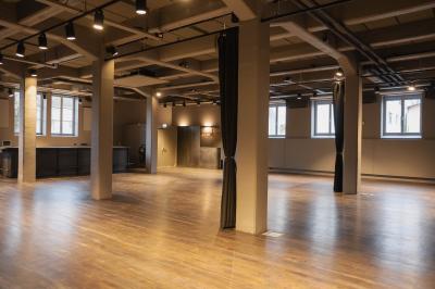 Un DJ mixe sur une scène éclairée par des lumières colorées, face à une foule dansante dans une salle sombre.