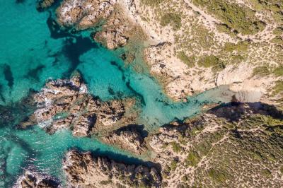 Paysage montagneux au coucher du soleil avec une personne debout sur un promontoire rocheux, entourée de végétation.