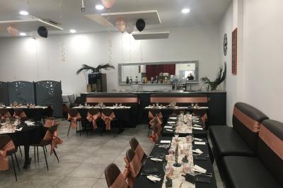 Comptoir de bar avec bouteilles alignées, verres, machine à café et décor sobre dans une pièce lumineuse.