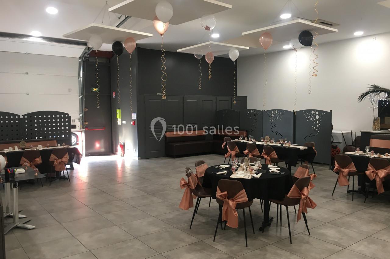 Salle de réception décorée avec des ballons et des tables dressées pour un événement festif.