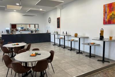 Comptoir de bar avec bouteilles alignées, verres, machine à café et décor sobre dans une pièce lumineuse.