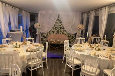 Un parc verdoyant avec des arbres feuillus et une allée ensoleillée menant à un bâtiment blanc au loin.