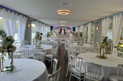 Un parc verdoyant avec des arbres feuillus et une allée ensoleillée menant à un bâtiment blanc au loin.