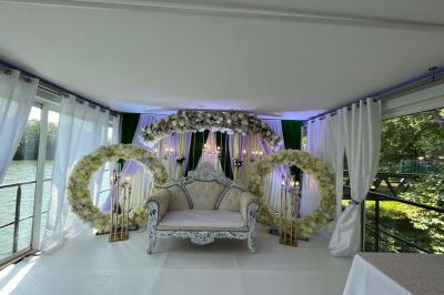 Un parc verdoyant avec des arbres feuillus et une allée ensoleillée menant à un bâtiment blanc au loin.