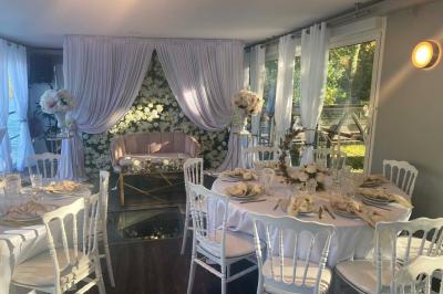 Un parc verdoyant avec des arbres feuillus et une allée ensoleillée menant à un bâtiment blanc au loin.