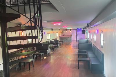 Un parc verdoyant avec des arbres feuillus et une allée ensoleillée menant à un bâtiment blanc au loin.