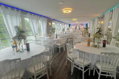 Un parc verdoyant avec des arbres feuillus et une allée ensoleillée menant à un bâtiment blanc au loin.