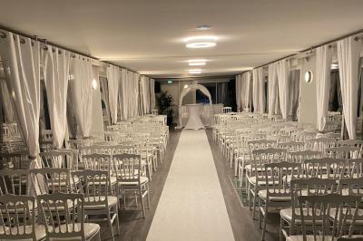 Un parc verdoyant avec des arbres feuillus et une allée ensoleillée menant à un bâtiment blanc au loin.