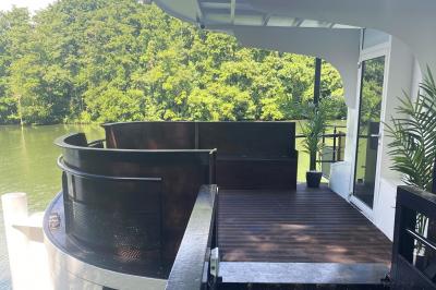 Un parc verdoyant avec des arbres feuillus et une allée ensoleillée menant à un bâtiment blanc au loin.