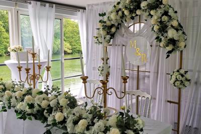 Un parc verdoyant avec des arbres feuillus et une allée ensoleillée menant à un bâtiment blanc au loin.