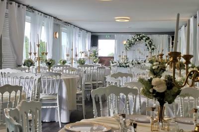 Un parc verdoyant avec des arbres feuillus et une allée ensoleillée menant à un bâtiment blanc au loin.
